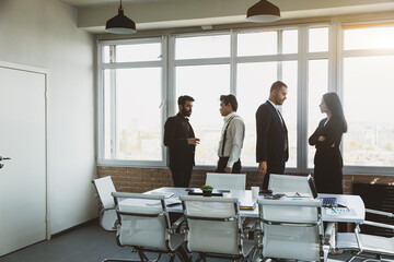 Wall Mural - Silhouettes of people against the window. A team of young businessmen working and communicating together in an office. Corporate businessteam and manager in a meeting.