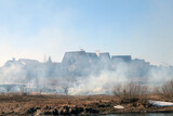 Fototapeta Natura - burning grass and smoke near houses