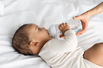 Cute little African American child drinking from baby bottle