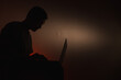 © vov8000 - Silhouette of a guy with a computer.Silhouette of a man on a red background.