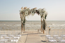 Outdoor Area For Beach Ceremonies With Sea View, White Chairs, Flower Arch On A Sunny Day