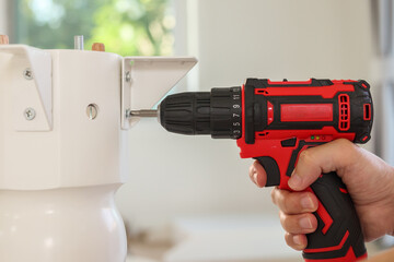 Wall Mural - man assembling white table furniture at home using cordless screwdriver