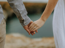 Close up of caucasian couple holding hands including engagement ring