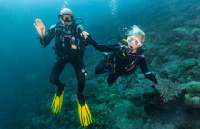 A Scuba Diving Couple Exploring The Tropical Waters Around Komodo