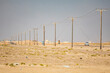 Middle East, Arabian Peninsula, Al Batinah South, Mahout. A power line and road in the desert of Oman.