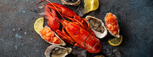 Seafood Assorted Plate With Cooked Red Whole Lobster, Fresh Open Oysters, Black Caviar, Salmon Tartare Served With Lemon Wedges And Ice Cubes Top View Flat Lay On Blue Concrete Stone Background