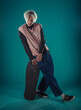 © qunica.com - Young adult man in casual outfit wear looking at camera, holding skateboard near face and standing at studio on blue background
