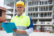 Portrait of a man project manager standing with folder with documents at construction site