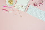Fototapeta Kwiaty - Woman working items with flowers, glasses, keyboard and lips over the pink background. 