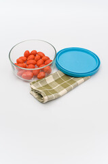 Poster - fresh organic datterini tomatoes in a glass bowl and table napkin on a white table background