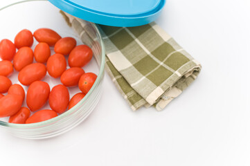 Poster - fresh organic datterini tomatoes in a glass bowl and table napkin on a white table background