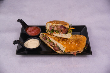 Poster - Closeup of a sandwich with ketchup and mayo on a black plate