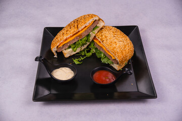 Poster - Closeup of a sandwich with ketchup and mayo on a black plate