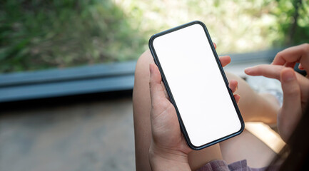 Wall Mural - woman hand using mobile phone with blank white screen in living room at home.