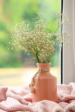 Vase With Gypsophila Flowers And Pink Plaid On Windowsill