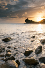 Wall Mural - Scenic view of a rocky beach at sunset