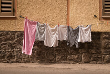 clothes hanging drying on a clothesline in street in italy near yellow wall