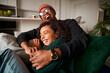 © StratfordProductions - Trendy multi-ethnic adult couple sitting on sofa laughing hysterically. High quality photo