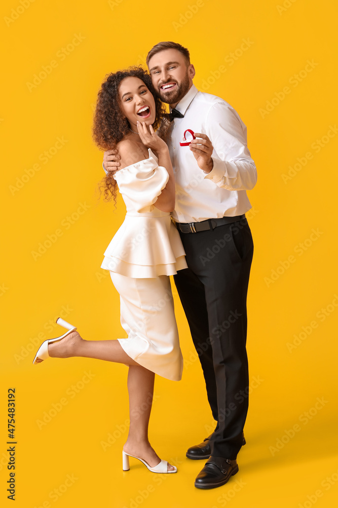 Happy young engaged couple on color background