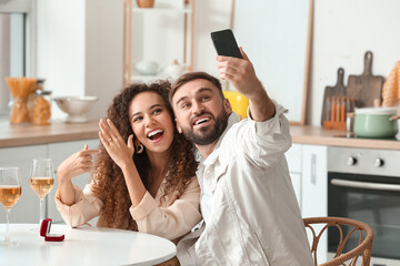 Poster - Happy young couple taking selfie after marriage proposal at home