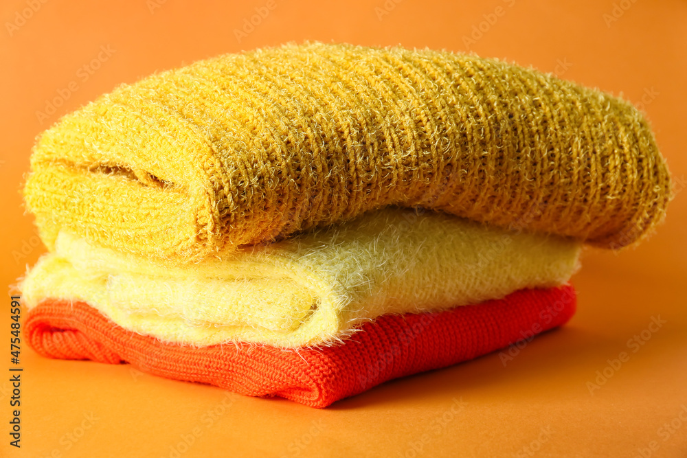 Stack of soft modern sweaters on color background