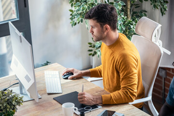 Fototapete - Graphic designer using a pen tablet while working with computer in modern startup office.