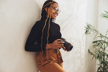 Young woman holding a dslr camera in her office