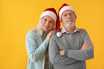 Poster - Happy mature couple in Santa hats on color background