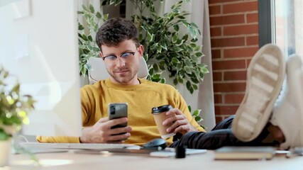 Fototapete - Video of  graphic designer working with computer while using smartphone and drinking coffee in modern startup office.