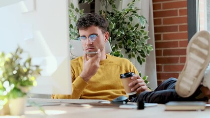 Fototapete - Video of  graphic designer working with computer while using smartphone and drinking coffee in modern startup office.