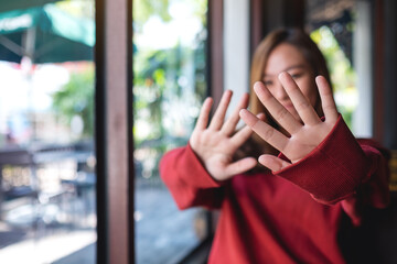 Wall Mural - A young asian woman outstretched hand and showing stop hand sign