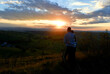 © GRADA - A young couple climbing a hill watching the beautiful sunset and landscape in the distance