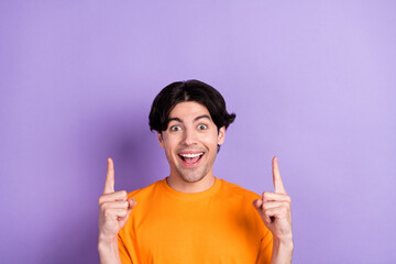 Canvas Print - Photo of positive young cheerful amazed man point fingers empty space up isolated on purple color background