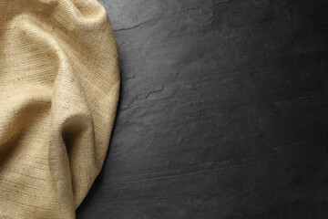 Natural burlap fabric on black table, top view. Space for text