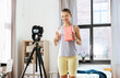 © Syda Productions - fitness, sport and video blogging concept - happy smiling teenage girl or blogger with camera on tripod and yoga block recording online class at home