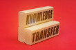 On a red background, wooden blocks with the inscription - KNOWLEDGE TRANSFER
