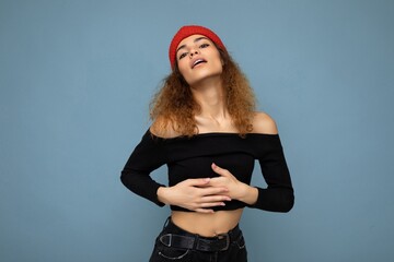 Wall Mural - Photo of pretty beautiful attractive positive sexy cool young curly dark blonde woman standing isolated over blue background wall with copy space for text wearing everyday trendy and stylish black top