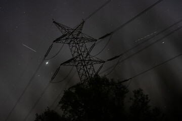 Wall Mural - Metal electricity pylon during the night on a cloudy sky background