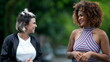 © Marco - Two happy diverse friends walking together outside in street laughing and smiling together