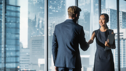 Female and Male Business Partners Meet in Office, Shake Hands. Corporate CEO and Finance Manager Have Meeting in City Office. Businesspeople Came to Discuss Real Estate Purchase and Marketing Project.