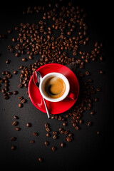 Canvas Print - Vertical shot of  a cup of coffee with roasted beans on a dark surface