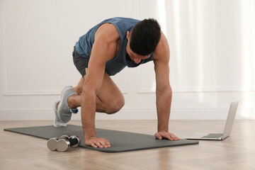 Poster - Handsome man doing abs exercise on yoga mat while watching online class indoors