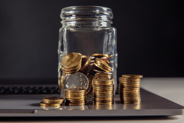 Finance and savings concept, money coin in jar on laptop close-up