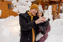 Happy Couple Taking Selfie In Front Of Ice Sculptures At Winter Resort