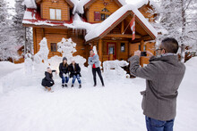 Man Photographing Family In Front Of Ice Sculptures At Snowy Resort