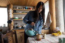 Woman Making Cup Of Tea In Cabin Kitchen