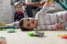 Cute Baby Girl Laying On Floor With Toys
