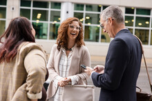 Businesswoman Laughing With Colleagues On Sidewalk