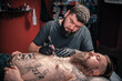 © Mr. Prof - Tattoo artist doing tattoo in tattoo parlour