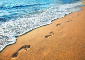 Wall Mural - beach, wave and footprints at sunset time